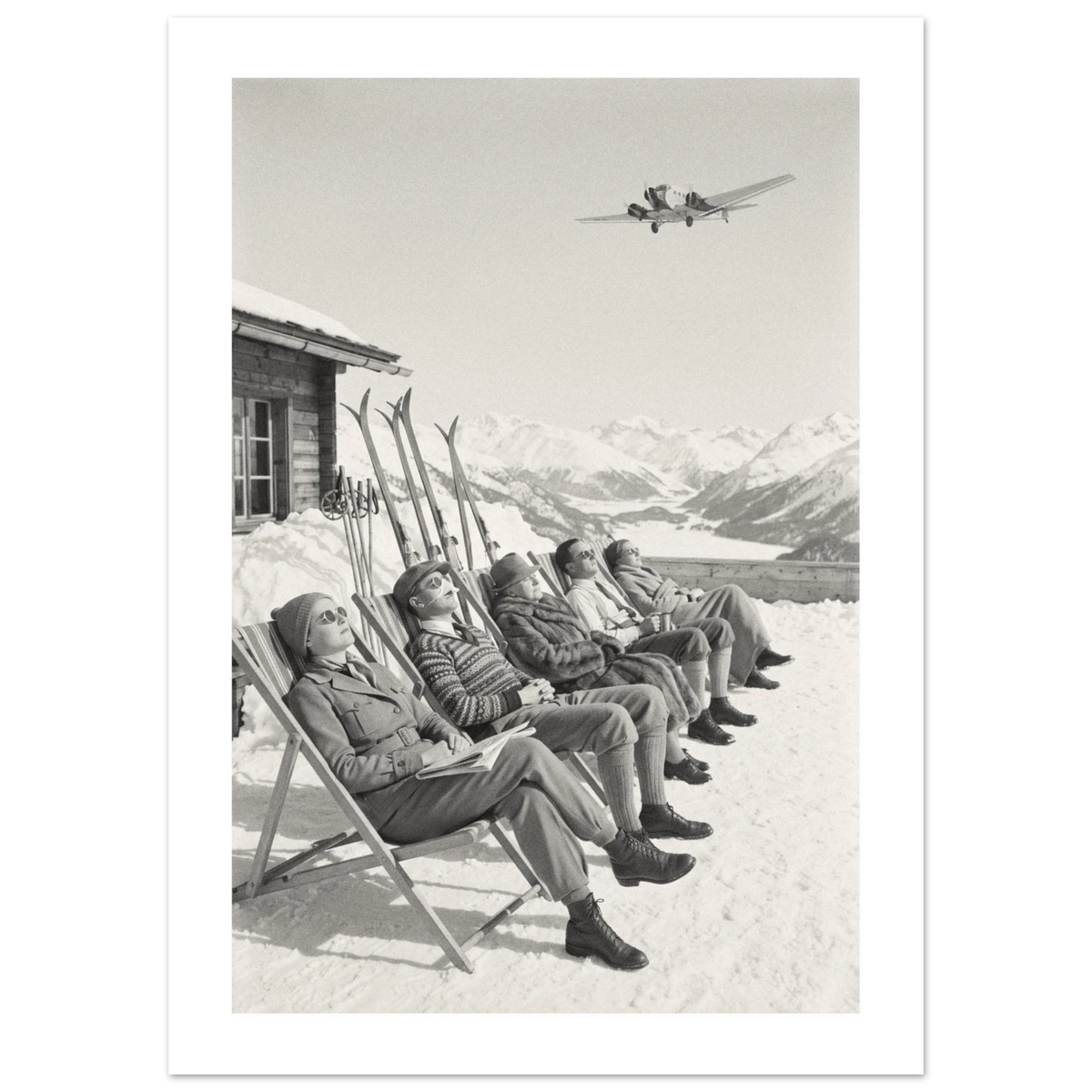 Five guests sunbathing in deckchairs on a snowy mountain terrace with an airliner overhead, 1934 style black and white photo print
