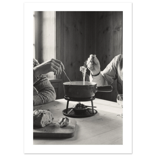 Couple dipping bread into a cheese fondue at a wooden table in a Swiss chalet room, 1932 style black and white photo print